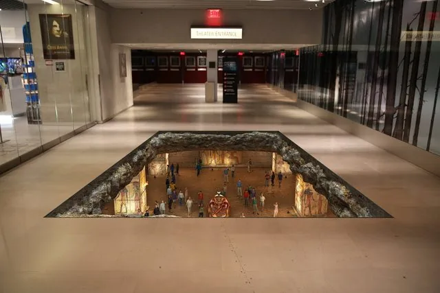 Photoreal trompe-l'oeil mockup of the Luxor lobby floor opening into an Egyptian tomb with a sarcophagus