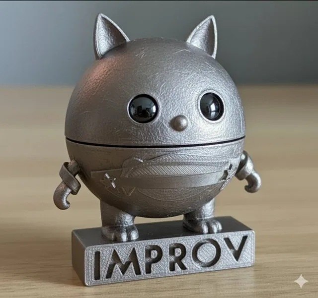 Concept render of a pewter figurine mascot: a round cat-eared ball creature standing on a base engraved IMPROV